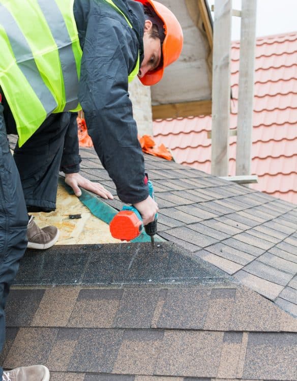 Roofer builder worker dismantling roof shingles